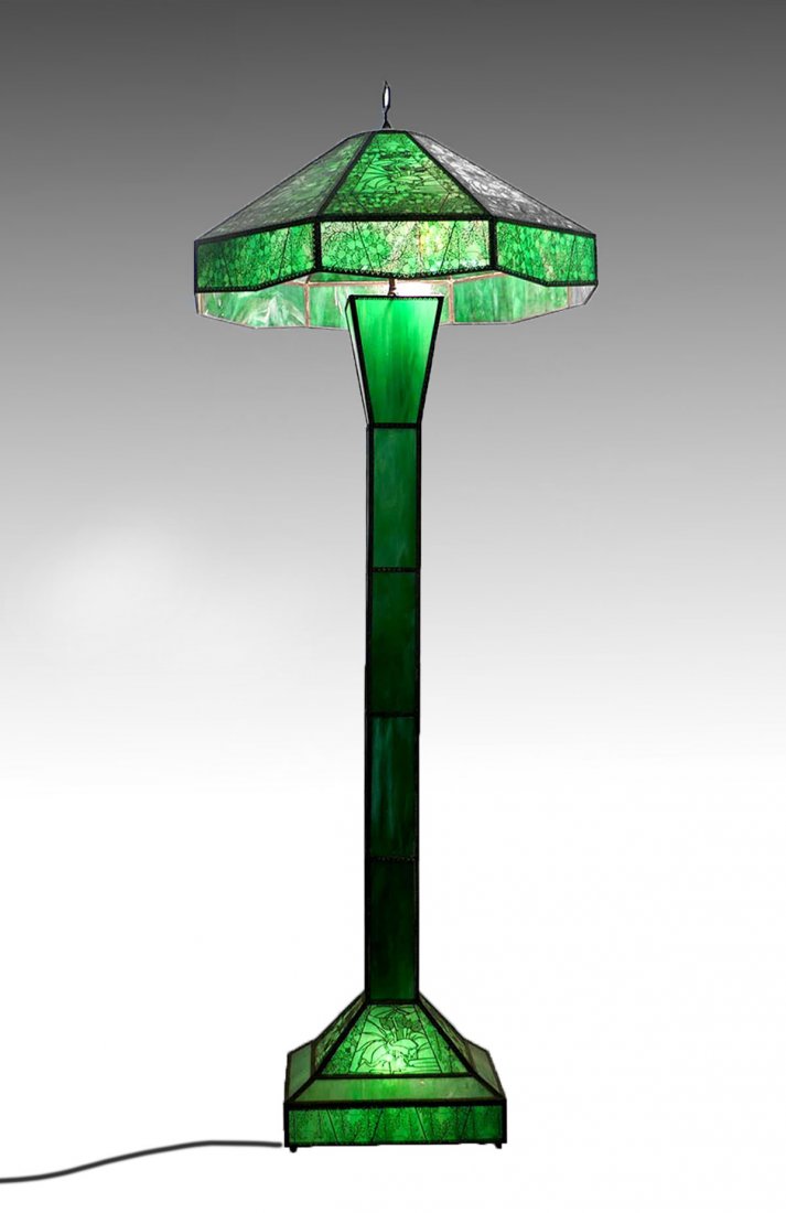 LARGE ETCHED METAL OVERLAY FLOOR LAMP: LARGE ETCHED METAL OVERLAY FLOOR LAMP: Attributed to Riviere Studios, this green slag glass with ornate etched metal overlay having scenes of floral & storks in a pond scene. Approx. 66.75" h x 27" w.
