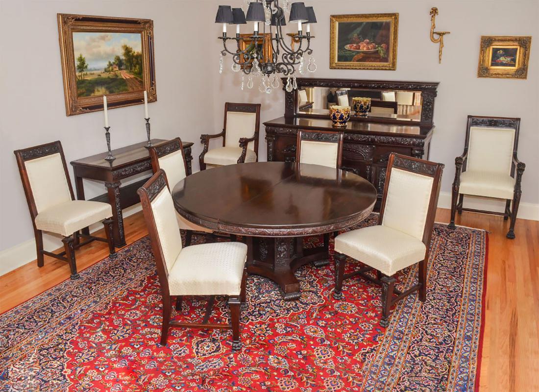 R. J. HORNER STYLE CARVED OAK DINING SUITE: R. J. HORNER STYLE CARVED OAK DINING SUITE: Comprising 1-Buffet having a beveled mirrored crest resting on a large sideboard Approx. 56" h x 72" l x 26.25" w., 1-round dining table having carved fruit