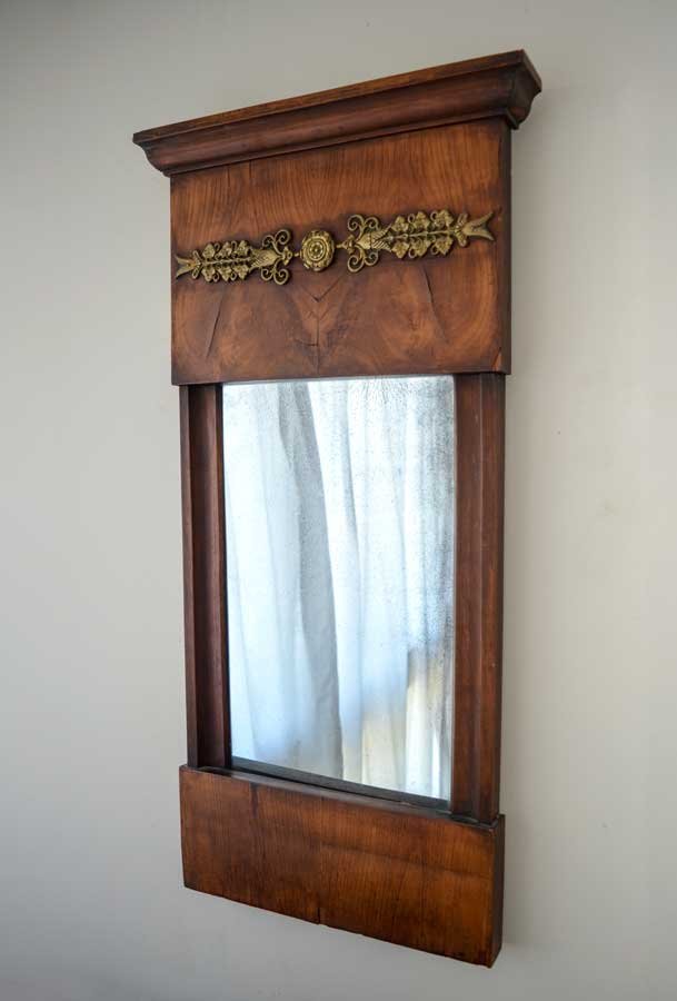 FRENCH EMPIRE WALL MIRROR: FRENCH EMPIRE WALL MIRROR: Mahogany match book veneer with a molded cornice and applied gilt metal foliate decoration. Approx. 32" h. x 16.25" l x 3" w.