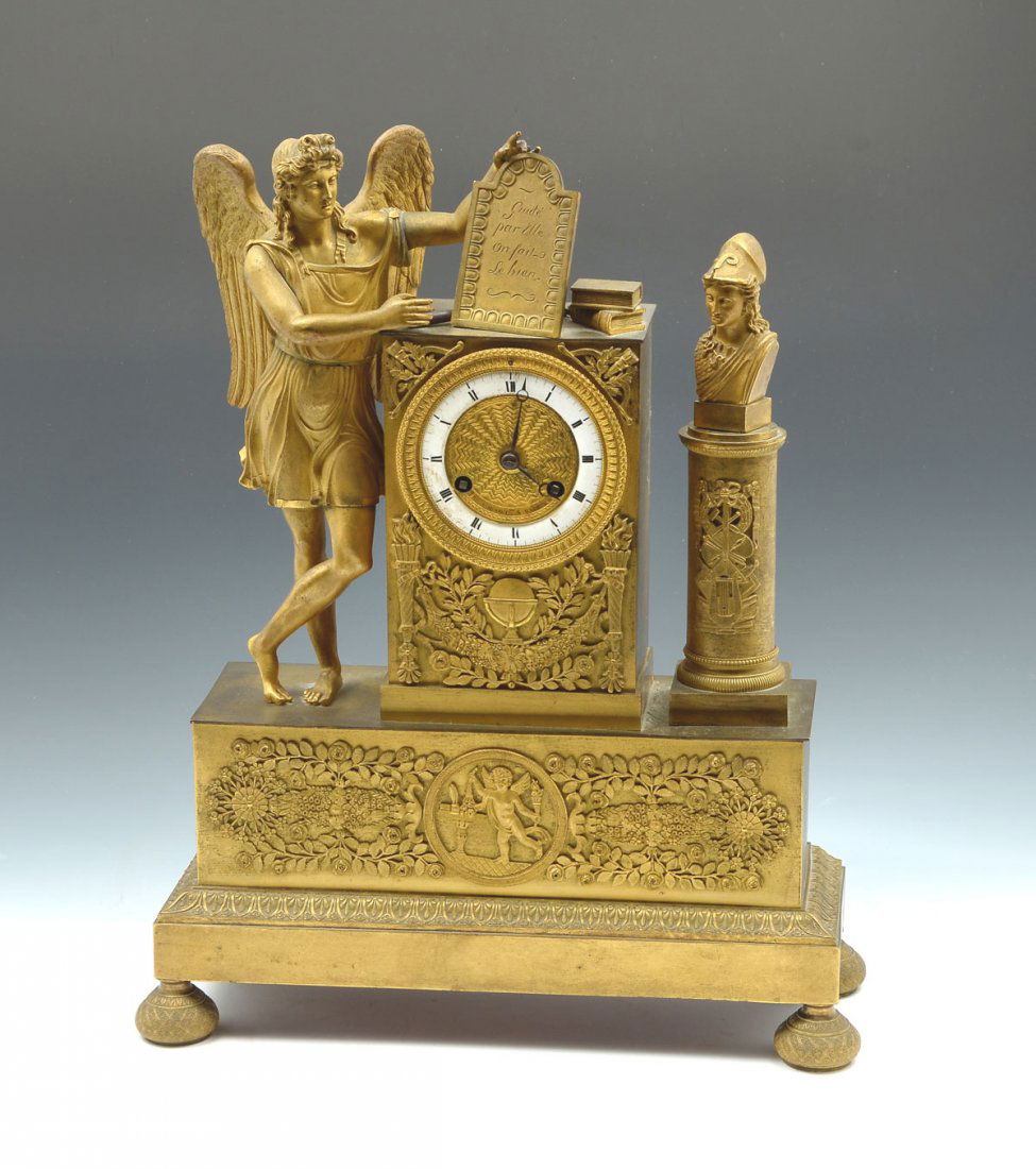 FRENCH DORE FIGURAL CLOCK: FRENCH DORE FIGURAL CLOCK: Surmounted by an angelic figure resting with hand on tablet, near books with a female bust on a column. White metal enameled face having roman numerals with a geometric cent