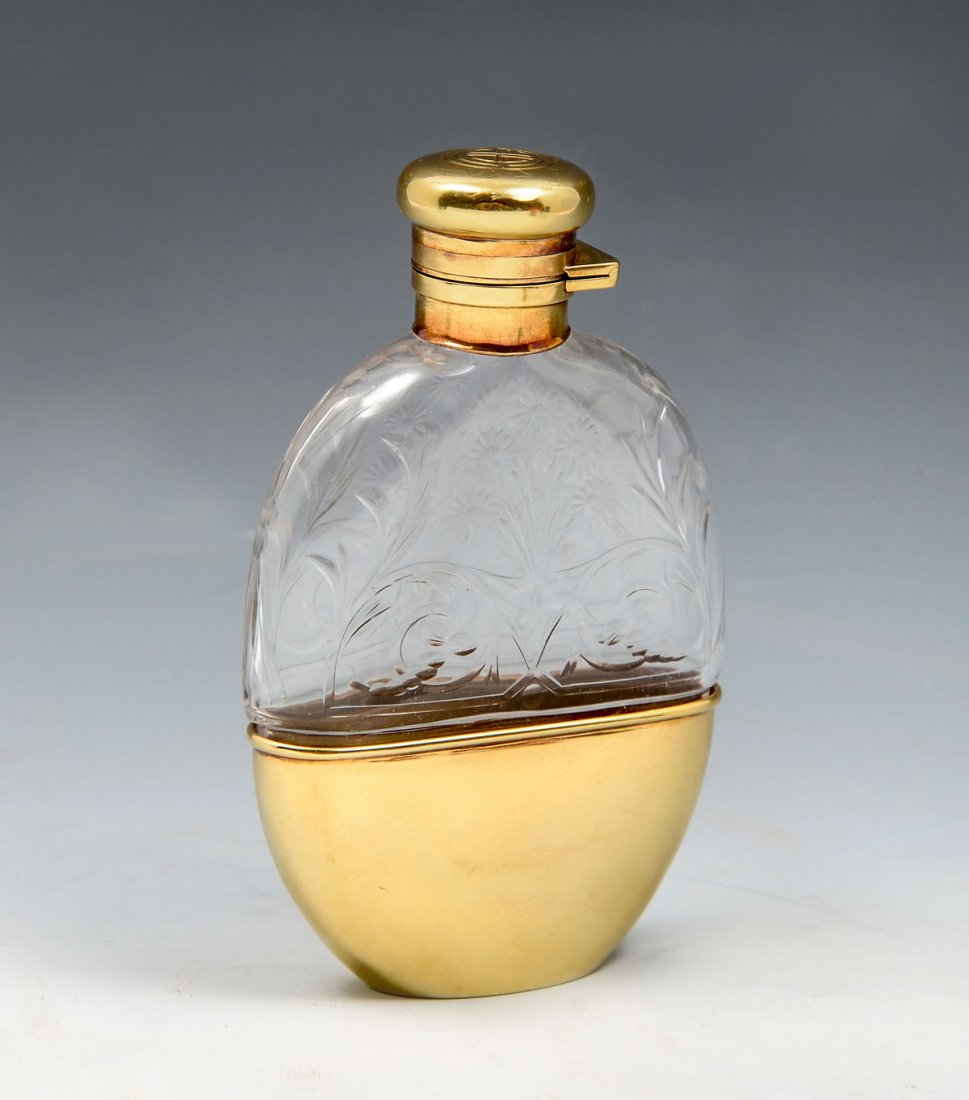 MEN'S CARTIER COLOGNE FLASK WITH 14K: MEN'S CARTIER COLOGNE FLASK WITH 14K: Glass flask with a floral design on upper portion and plain glass bottom that allows the flask to sit into a 14K holder, measures 4" H x 2.50" W. 14K is marked Ca