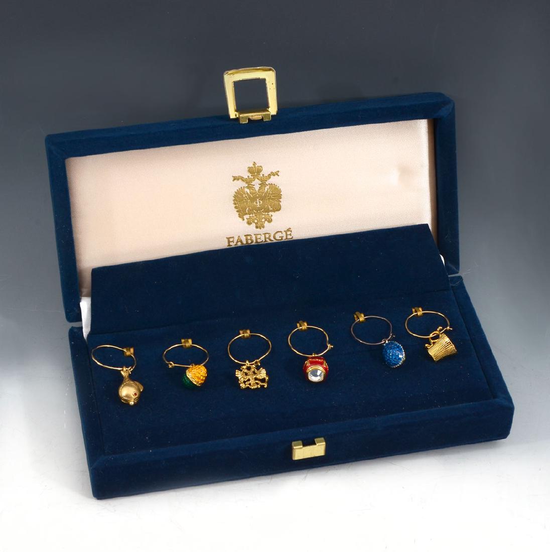 FABERGE LTD EDITION WINE GLASS CHARMS: FABERGE LTD EDITION WINE GLASS CHARMS: Set of 6 Faberge wine glass charms in a velvet box. Each charm is different - 3 different eggs, 1 cup, 1 fish and 1 Faberge logo. Ring - 1''. All in a blue velve