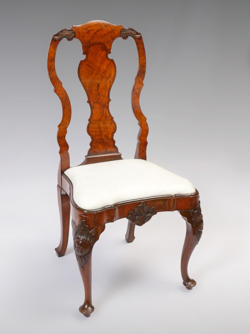 EARLY 18TH C. QUEEN ANN CHAIR: EARLY 18TH C. QUEEN ANN CHAIR: Queen Anne chair having a burlwood splat, carved scrolling medallion at skirt, upholstered in white. Raised on cabriole legs with carved figural knees and Dutch club fee