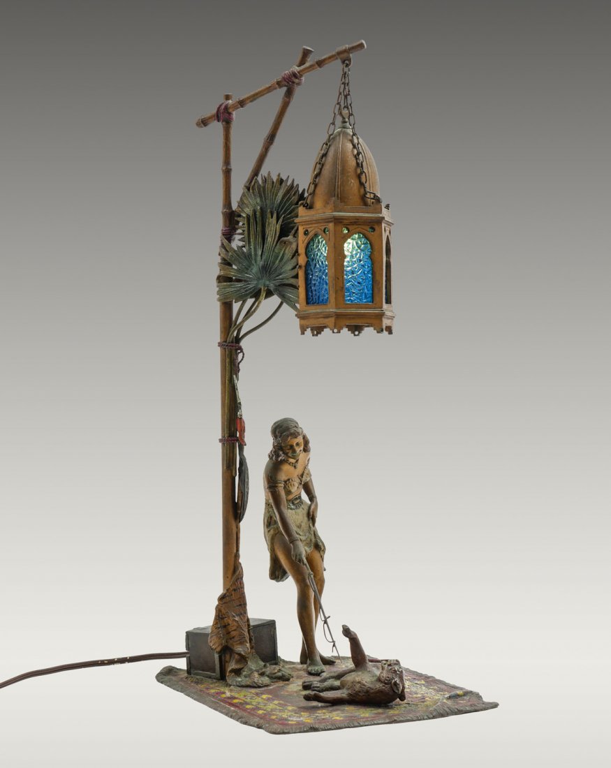 ANTON CHOKTA LION TAMER BRONZE LAMP: ANTON CHOKTA LION TAMER BRONZE LAMP: Cold painted bronze lamp by Anton Chotka, Austrian (1875-1925), depicting a female lion tamer & lion on a Persian carpet beneath a lamp having textured blue glass 