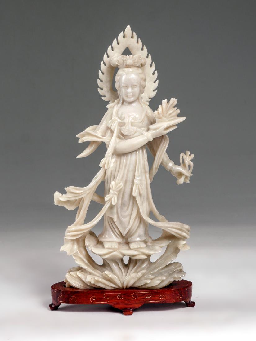 CARVED CHINESE WHITE JADE QWAN-YIN: CARVED CHINESE WHITE JADE QUAN-YIN: Finely carved Quan-Yin standing on a lotus and foliate. Rests on a fitted base with inlaid scrolling wire work. Approx. 9.5'' h x 5'' l x 2'' w.