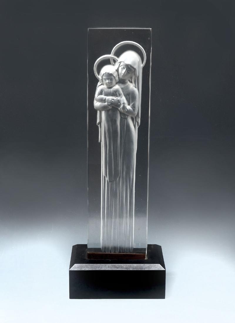 LALIQUE ''VIERGE A L'ENFANT'': LALIQUE "VIERGE A L'ENFANT": Deeply etched Lalique Intaglio plaque of "Vierge a L'Enfant" mounted on an ebonized base. Etched Lalique, France. Approx. 14.75" h x 5.5" l x 3.5" w.