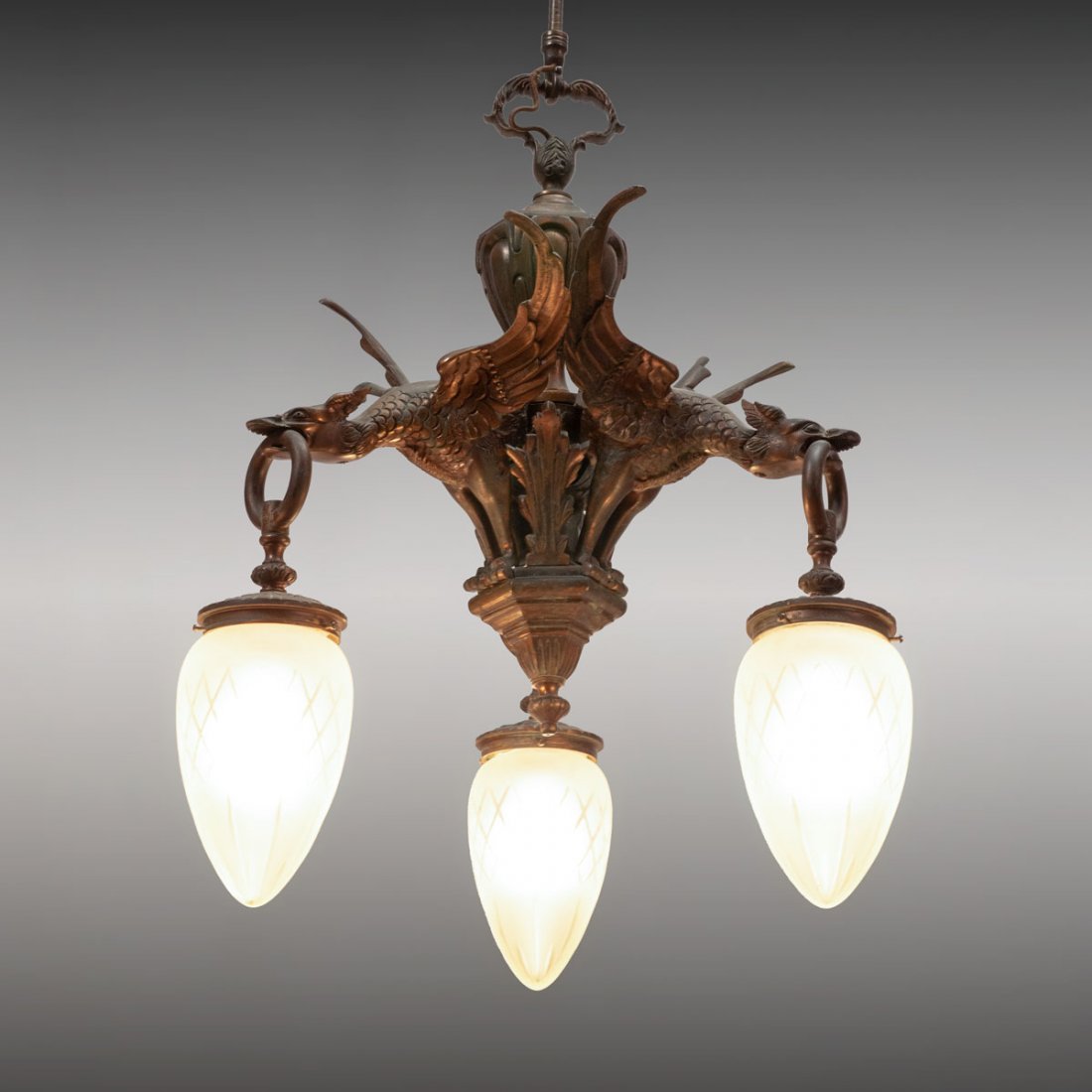 GOTHIC VICTORIAN DORE BRONZE GRIFFIN/DRAGON CHANDELIER: 3 LIGHT GOTHIC VICTORIAN DORE BRONZE GRIFFIN/DRAGON CHANDELIER: 3 light Victorian chandelier having 3 Griffin/Dragon like beasts with rings hanging from mouth having egg shaped & cut satin globes. App