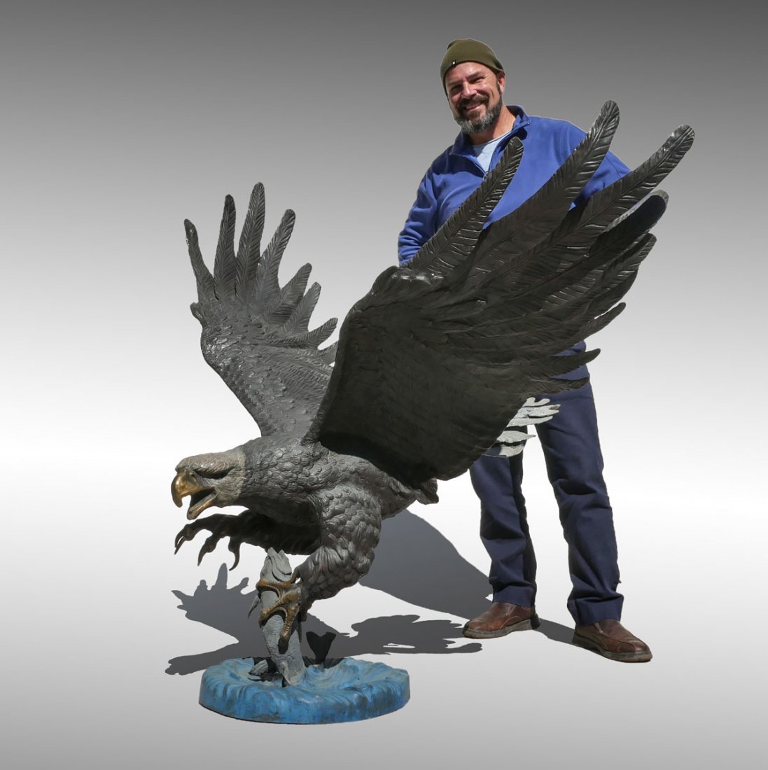 LIFESIZE PATINATED AMERICAN BALD EAGLE BRONZE: LIFESIZE PATINATED AMERICAN BALD EAGLE BRONZE: Approx. 52" at its highest point, 60" at its widest point, depicts the noble bird with wings spread and talons filled with trout, signed on the base by M