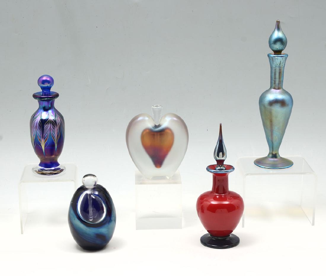 5 ART GLASS PERFUME BOTTLE COLLECTION: 5 ART GLASS PERFUME BOTTLE COLLECTION: Comprising; 1 blue iridescent bottle and stopper, signed, Lundberg, 1987, 1- heart shaped iridescent bottle with stopper, signed, Zellique 1984, 1- cobalt & purp