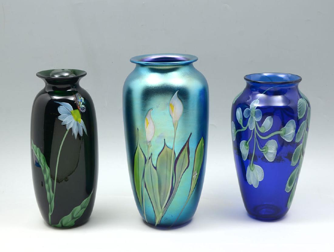 3 ORIENT AND FLUME VASES: 3 ORIENT AND FLUME VASES: Comprising 1 dark green vase with Daisy's & butterflies, 1 Cobalt blue vase having blossomed floral & foliate motif, & 1 Iridescent Calla Lily designed vase. All 3 made by Or