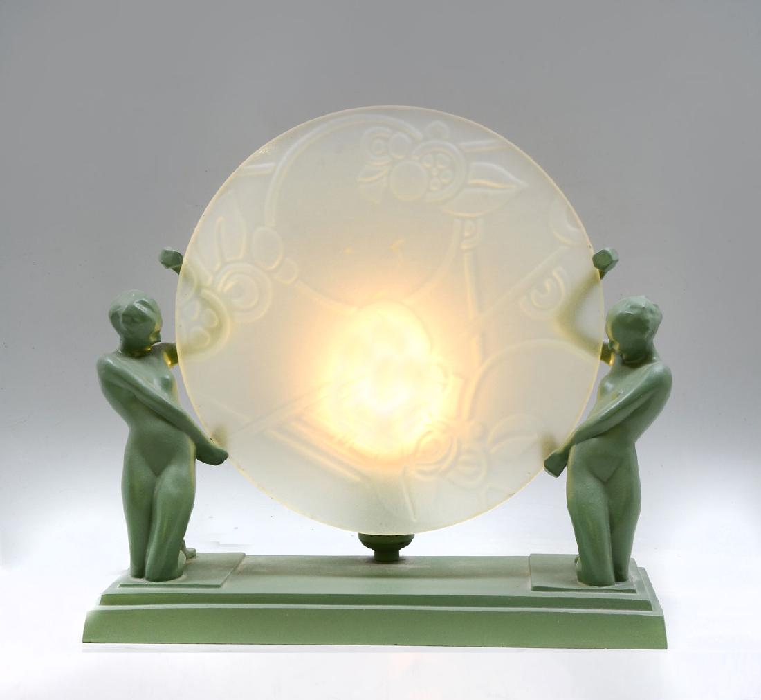 FRANKART DOUBLE NUDE FEMALE DISK LAMP: FRANKART DOUBLE NUDE FEMALE DISK LAMP: Art deco Frankart lamp having 2 opposing kneeling nude women holding a frosted disc shaped shade having a raised floral & foliate design. Approx. 12'' h x 12.75'