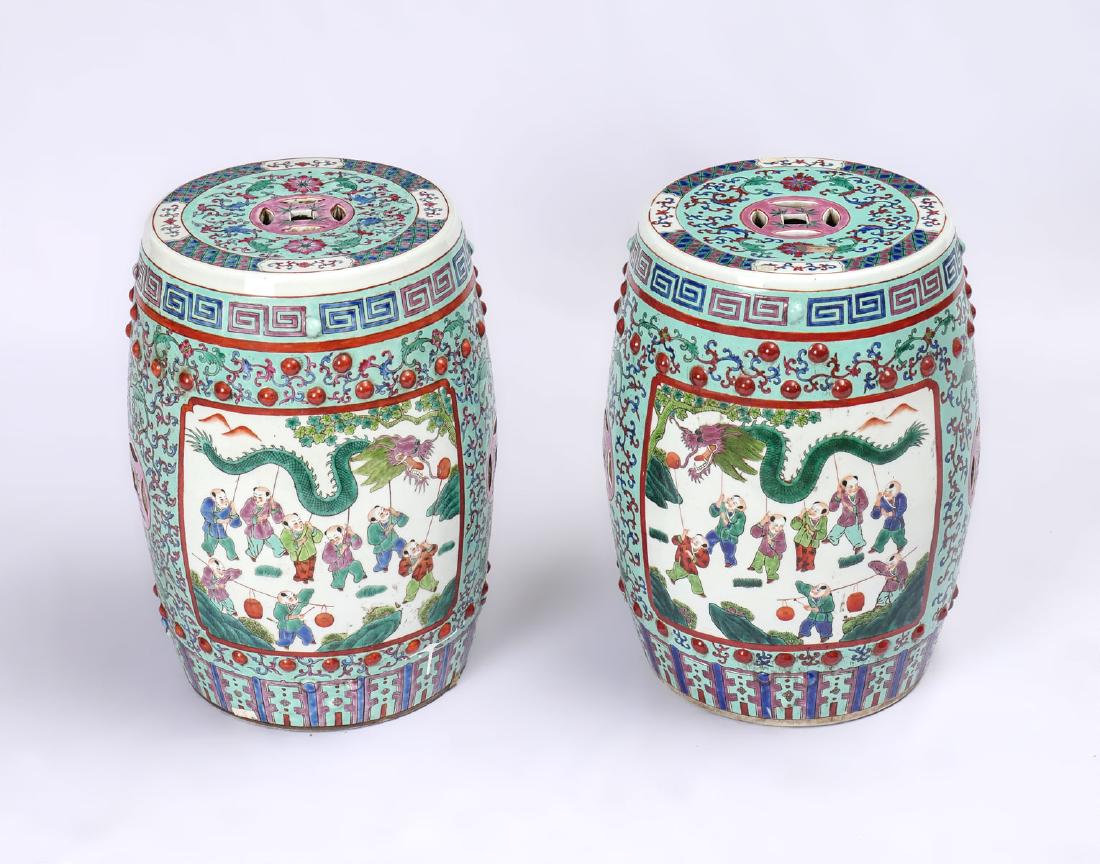 OPPOSING CHINESE FAMILLE ROSE GARDEN SEATS: OPPOSING CHINESE FAMILLE ROSE GARDEN SEATS: 2 Famille Rose opposing garden seats with a blue ground having windows with young warriors parading the Pearl of Wisdom being chased by a Dragon. Approx. 19