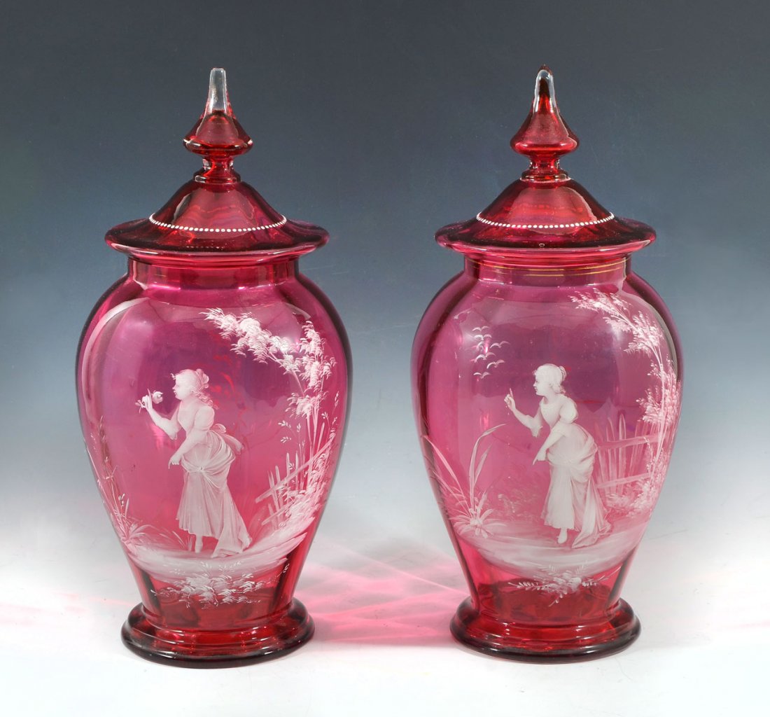2 LARGE MARY GREGORY COVERED JARS: 2 LARGE MARY GREGORY COVERED JARS: 2 optic panel cranberry glass lidded vases having a woman in a garden enameled scene & a beaded enameled encompassing at lid of each. Approx. 15.5" h x 7.5" w. Prove