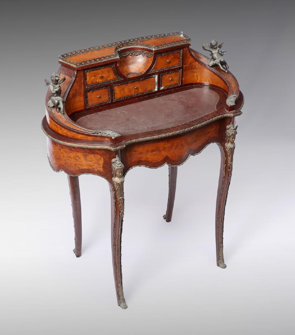 LOUIS XV STYLE FIGURAL ORMOLU MOUNTED DESK: LOUIS XV STYLE FIGURAL ORMOLU MOUNTED DESK: Louis XV style desk with a surmounting pierced border, over 5 drawers, flanked by curved sides having mounted cherubs holding a bird. Burlwood accents, Fema