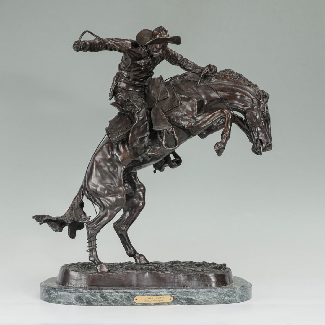 BRONCO BUSTER BRONZE AFTER FREDERIC REMINGTON: BRONCO BUSTER BRONZE AFTER FREDERIC REMINGTON: 20" in height, affixed to beveled marble plinth, 22" in height x 18.50" wide overall.