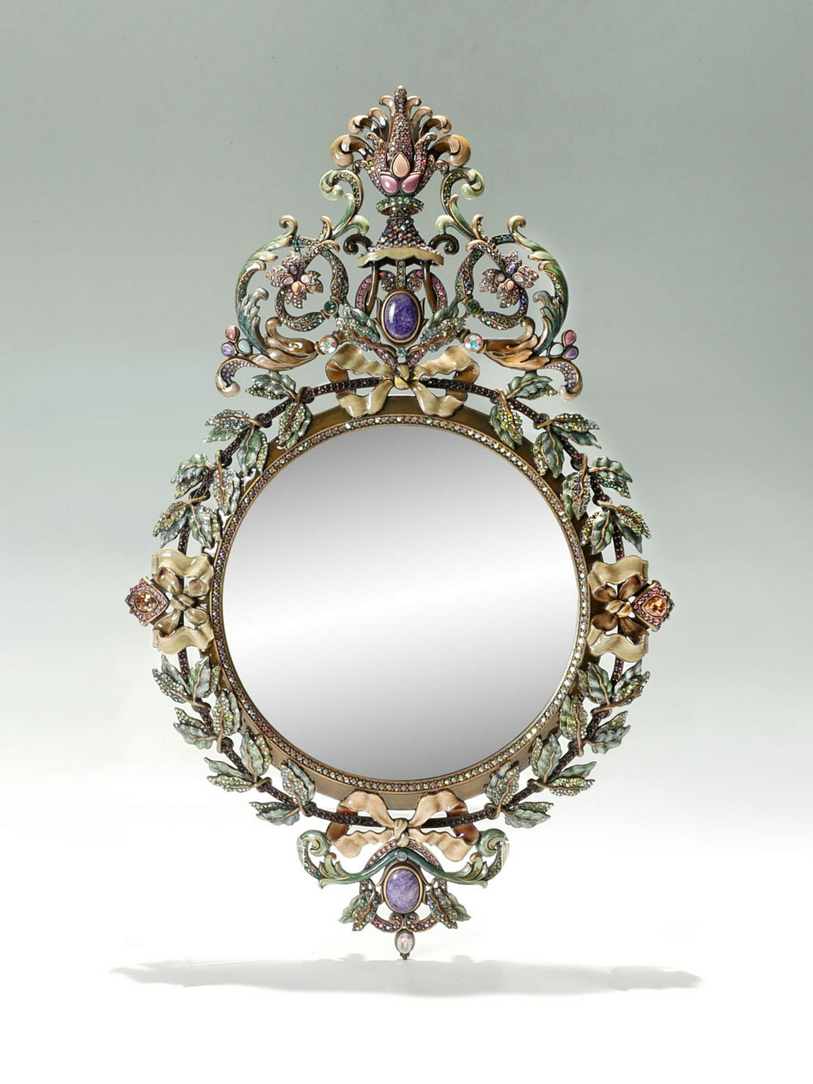 JAY STRONGWATER ENAMELED & JEWELED MIRROR: JAY STRONGWATER ENAMELED & JEWELED MIRROR: Enameled wall mirror by Jay Strongwater having an encompassing enameled scrolling foliate design with ribbons and 2 Amethyst stones. Jay Strongwater impresse