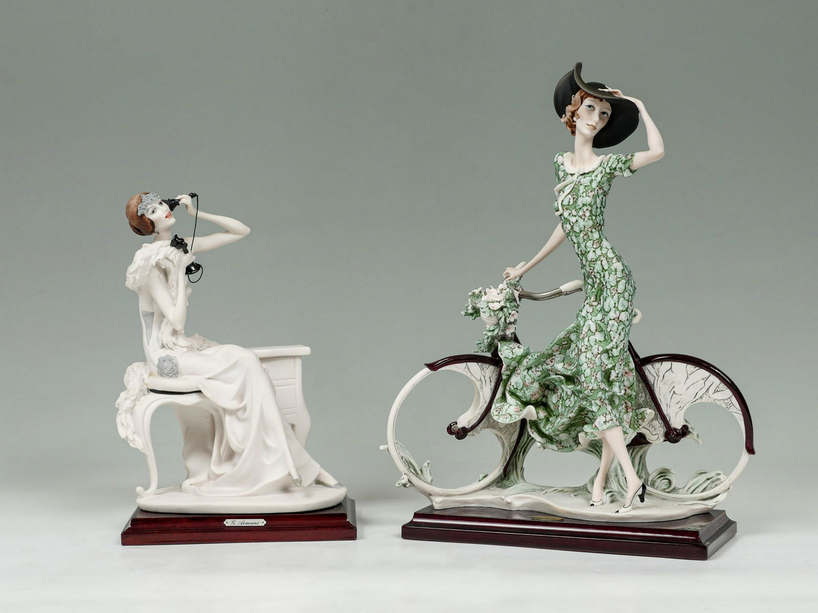 PAIR OF GIUSEPPE ARMANI ART DECO FIGURES: PAIR OF GIUSEPPE ARMANI ART DECO FIGURES: Comprising 1- Woman resting on a stool while talking on the phone, & 1- Woman standing next to her bike with a basket full of spring flowers. Both are made by
