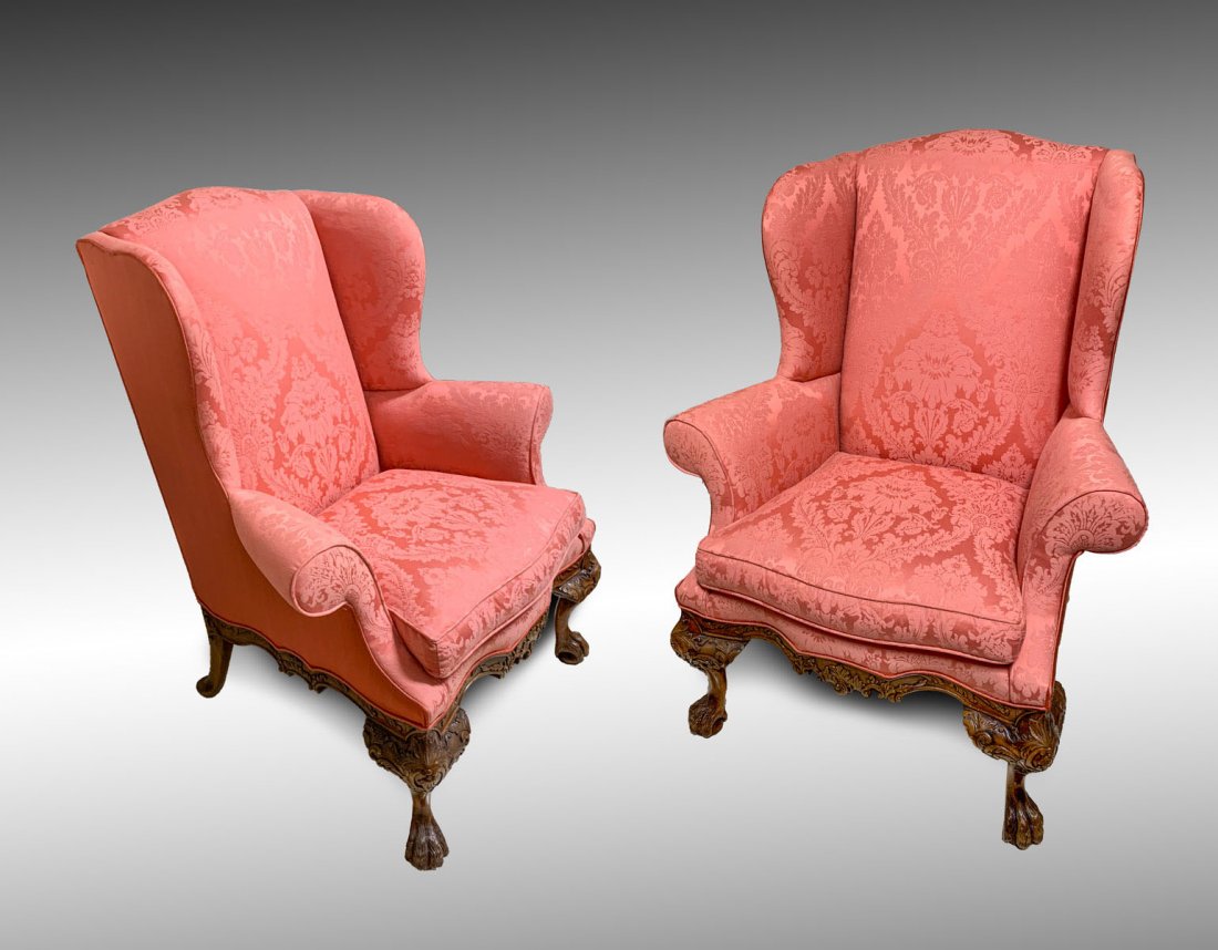 PR HIGHLY CARVED WINGBACK CHAIRS: PR HIGHLY CARVED WINGBACK CHAIRS: 2 Ornately carved wingback chairs upholstered in a coral colored scrolling foliate pattern. Carved foliate skirt, raised on rear dutch feet and front cabriole legs wi