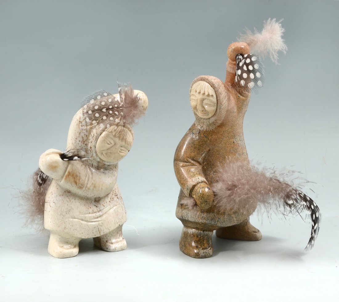 2 INUIT ESKIMO STONE CARVED DANCING FIGURES W/ FEATHERS: 2 INUIT ESKIMO STONE CARVED DANCING FIGURES WITH FEATHERS: 2 Inuit Eskimo carved hardstone dancing figures with attached faces. Both are holding spotted feathers. Both have marks at the underside of o