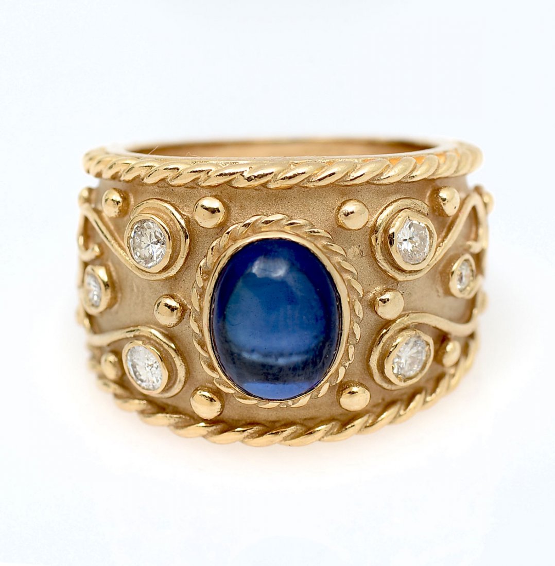 18K RING ETRUSCAN REVIVAL SEMI-DOMED CIGAR BAND RING: 18K RING ETRUSCAN REVIVAL SEMI-DOMED CIGAR BAND RING: 3.7 CT oval high cabochon lab grown sapphire has a rich blue kashmir color and is featured in this .625" cigar band 18K ring. 6 diamonds approx .5