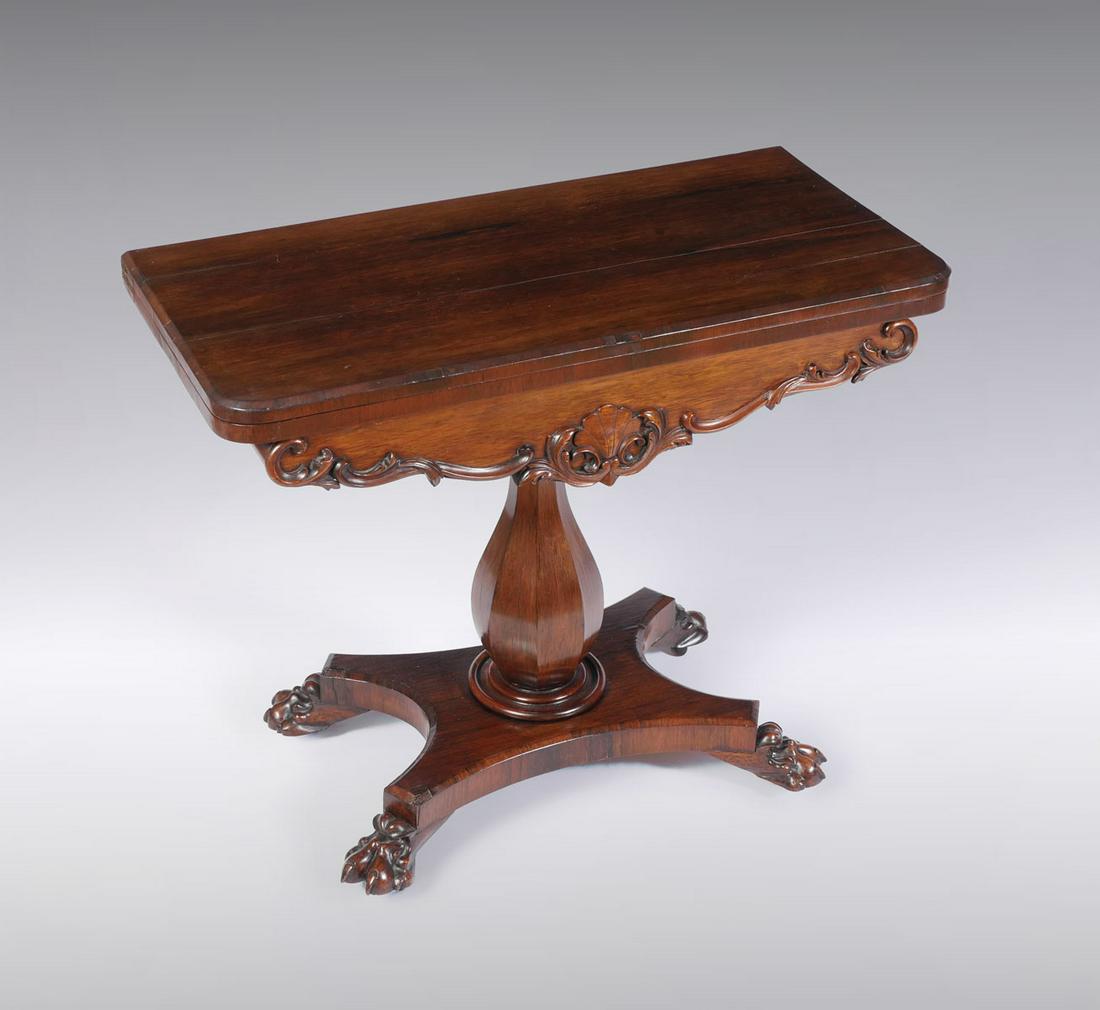 CARVED EMPIRE CLAW FOOT GAME TABLE: CARVED EMPIRE CLAW FOOT GAME TABLE: Empire game table having a round red felt playing surface. Top swings to reveal a game storage compartment. Carved Shell medallion, flanked by scrolling foliate. Ra