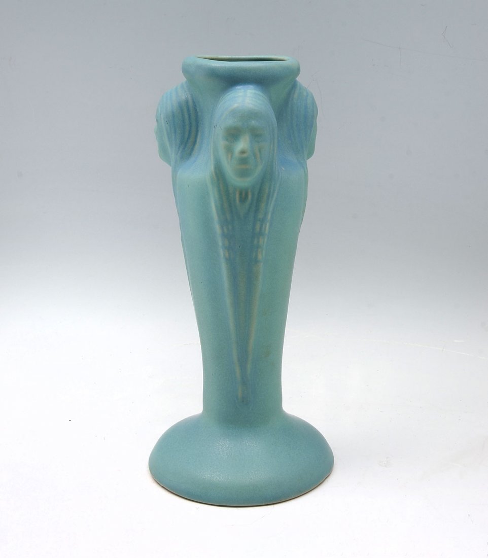 VAN BRIGGLE THREE INDIAN HEAD VASE LAMP BASE VASE: VAN BRIGGLE THREE INDIAN HEAD VASE LAMP BASE VASE: Sea Foam ground Van Briggle vase/lamp base, having 3 Native American faces with blue spray. Incised signature & marks at underside. Approx. 12.25" h 