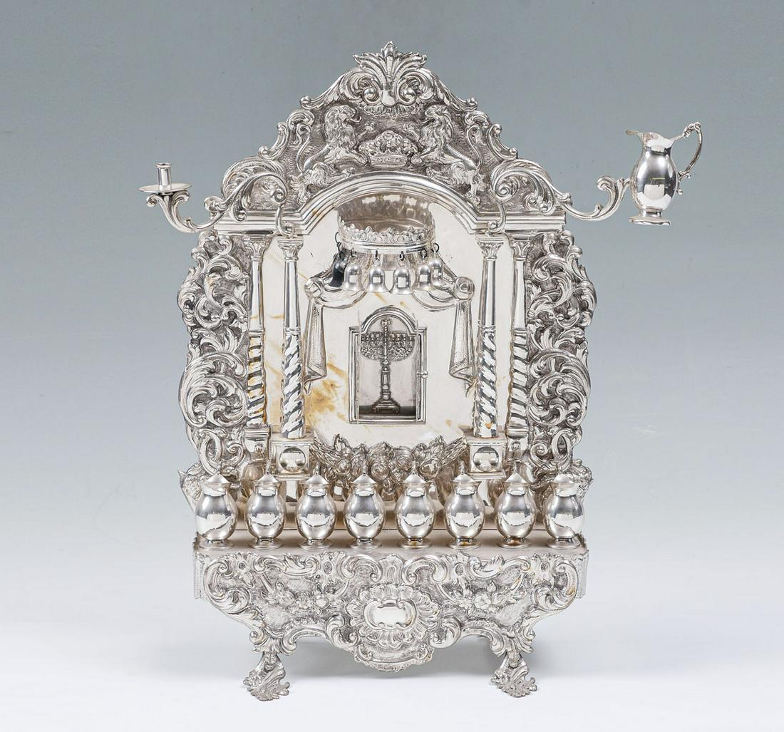 TALL STERLING HANUKKAH LAMP MENORAH: TALL STERLING HANUKKAH LAMP MENORAH: Surmounted by a scrolling foliate designed crest with a crawn in center, flanked by lions. 8 pitchers mounted to scrolling foliate base, under pillars flanking 2 d