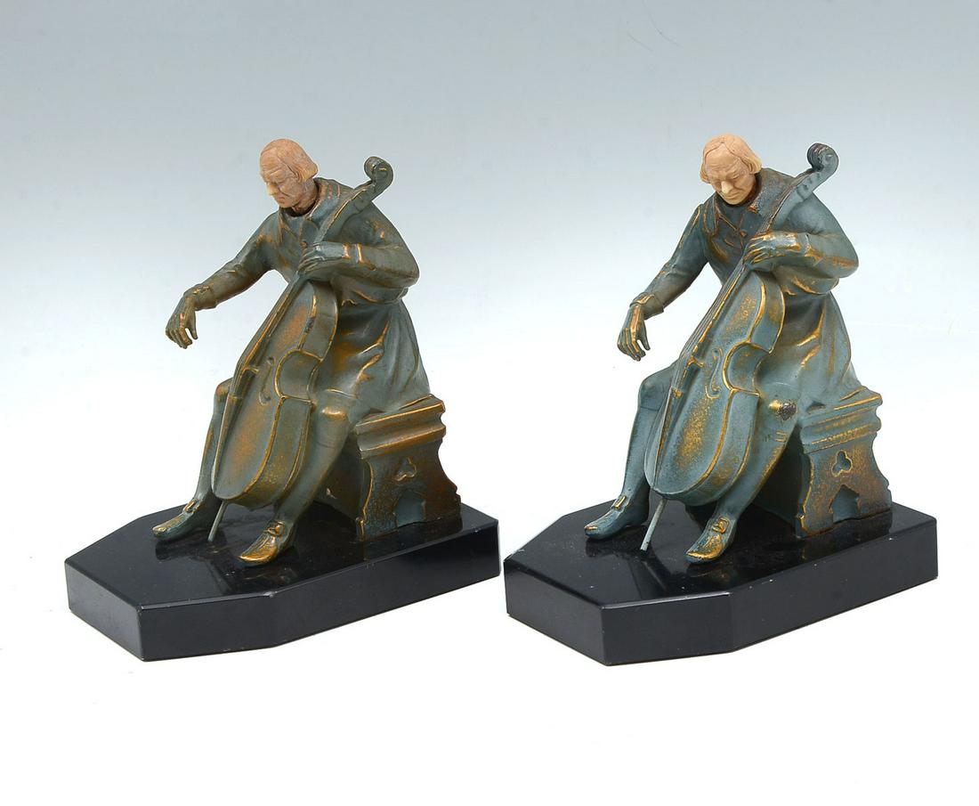 J. RUHL 1932 CELLO PLAYER BOOKENDS: J. RUHL 1932 CELLO PLAYER BOOKENDS: Pair of John Ruhl bookends by JB Hirsch, of a seated cellist with a carved celluloid head. Mounted on a black metal base. Stamped at verso, JBH,1932 and initialed J
