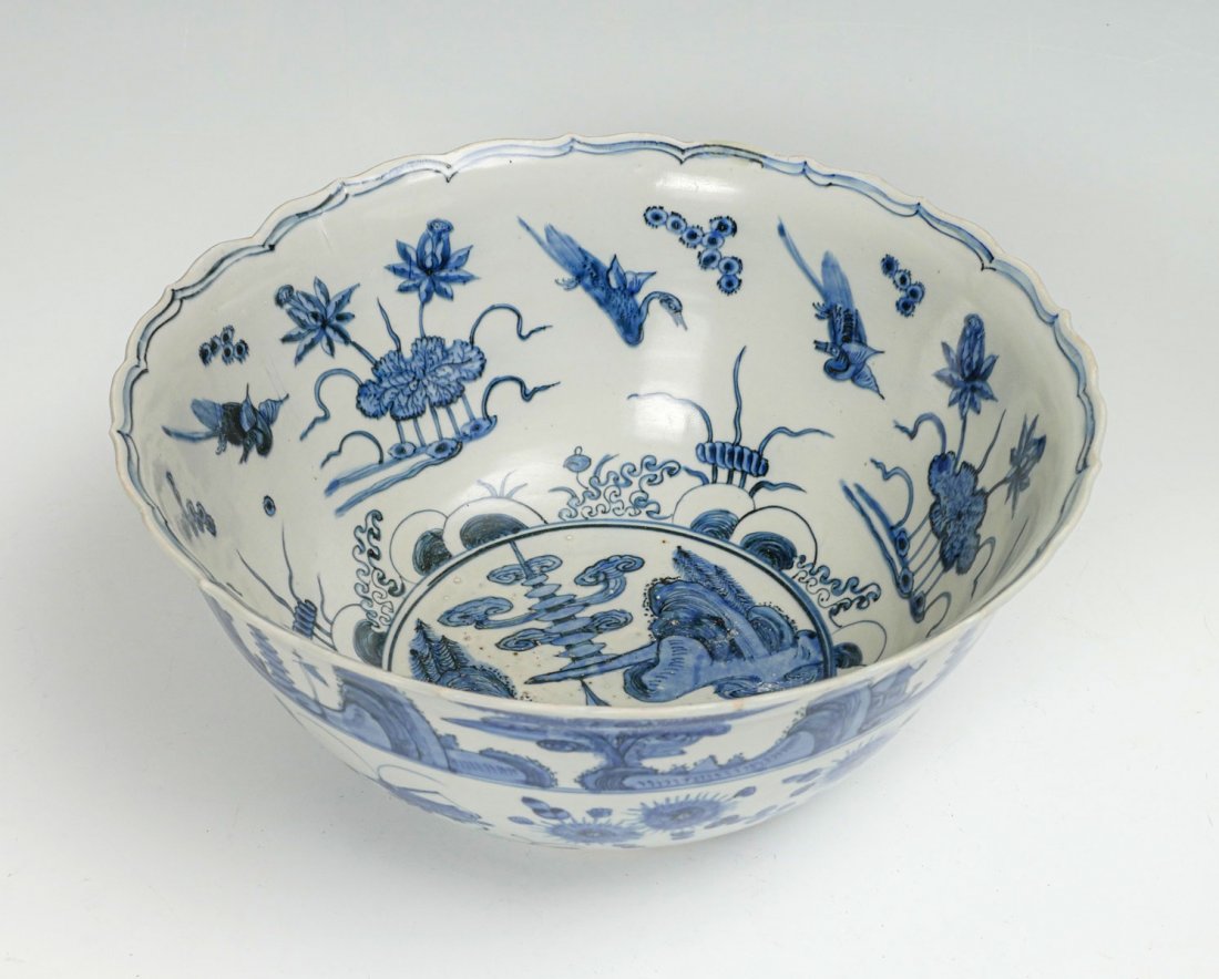 MING DYNASTY BLUE & WHITE BOWL: MING DYNASTY BLUE & WHITE BOWL: Large mid-Ming dynasty bowl circa 1550-1575, having a shaped rim with a blue & white floral & bird design. Interior has a central mountainous village scene, and exterio