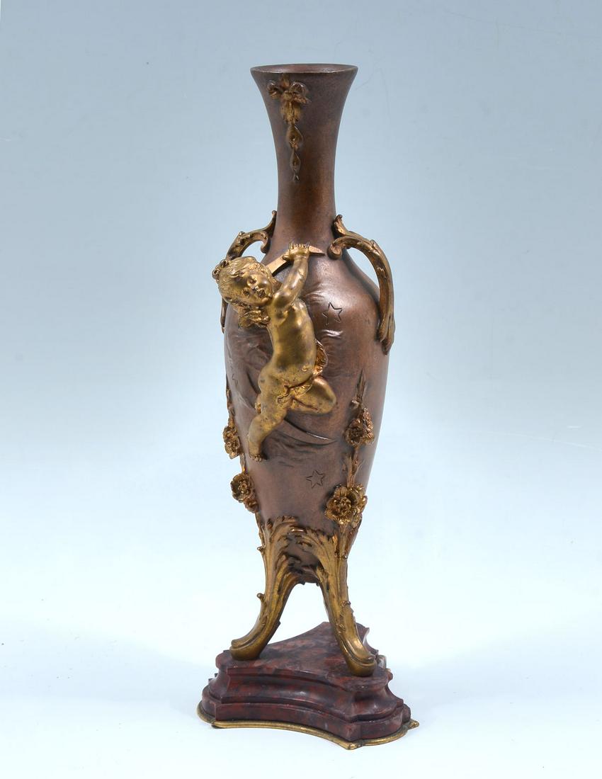 AUGUSTE MOREAU BRONZE PERIOD VASE: AUGUSTE MOREAU BRONZE PERIOD VASE: Bronze handles vase with Putti, having gilt foliate accents. Mounted in a beveled Brick Red marble base. Incised signature Auguste Moreau. Approx. 14.25" h x 5" w.