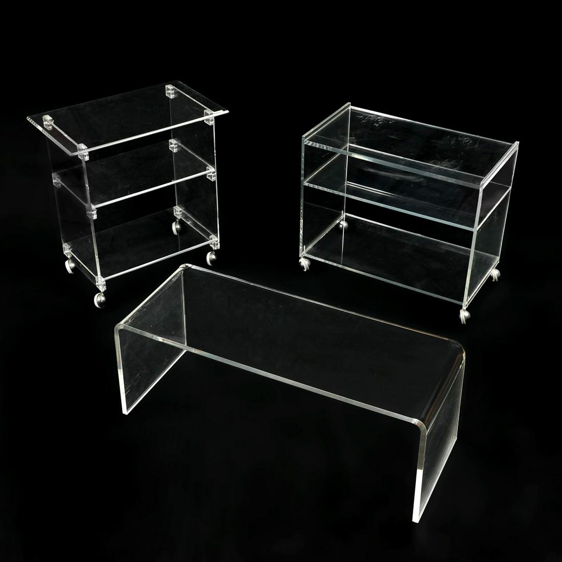 3 PC. LUCITE COFFEE TABLE AND TEA CARTS: 3 PC. LUCITE COFFEE TABLE AND TEA CARTS: Comprising; 2- Lucite tea/drink carts on casters & 1- bent Lucite coffee table. Largest Approx. 28.5'' x 27'' l x 16'' w.