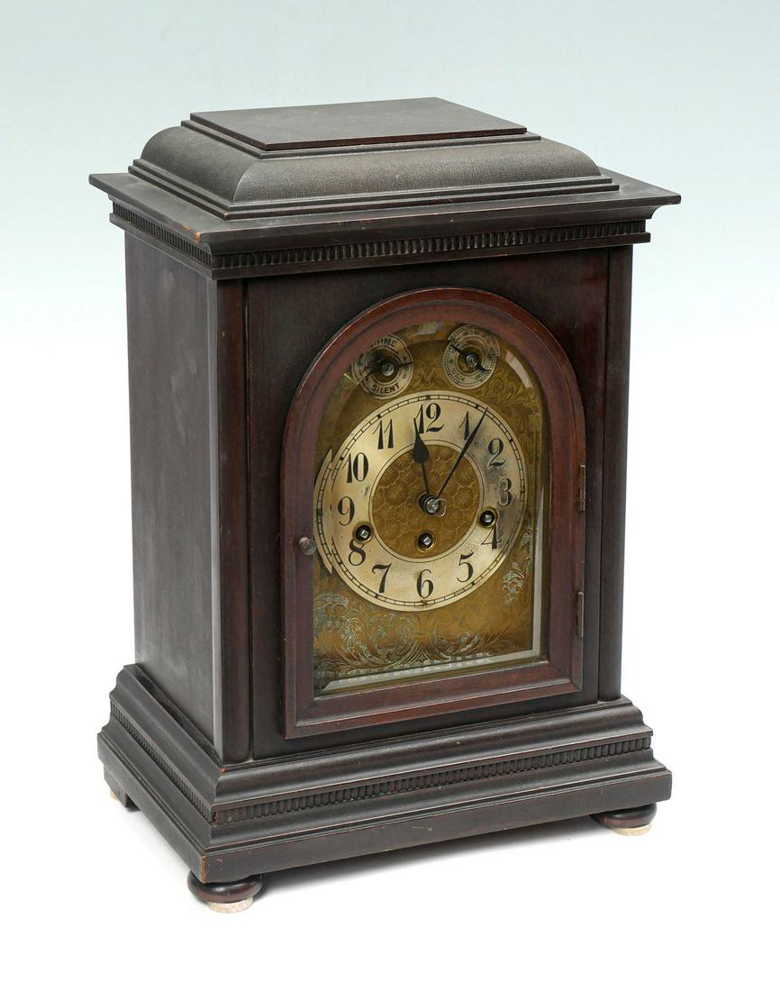 GERMAN JUNGHANS MANTLE CLOCK: GERMAN JUNGHANS MANTLE CLOCK: Circa 1900 German mantle clock, by Junghans of Baden-Wurttemberg, southwest Germany. Brass scrolling foliate face under a beveled arch shaped door. Approx. 17'' h x 12''