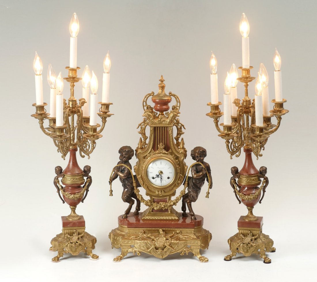 GILT IMPERIAL CLOCK GRANITURE: GILT IMPERIAL CLOCK GRANITURE: 20th C. 3 pc. Gilt metal and marble clock garniture with German movement. Comprising; A mantel clock & a pair of figural seven-light electrified candelabra, marked Imper