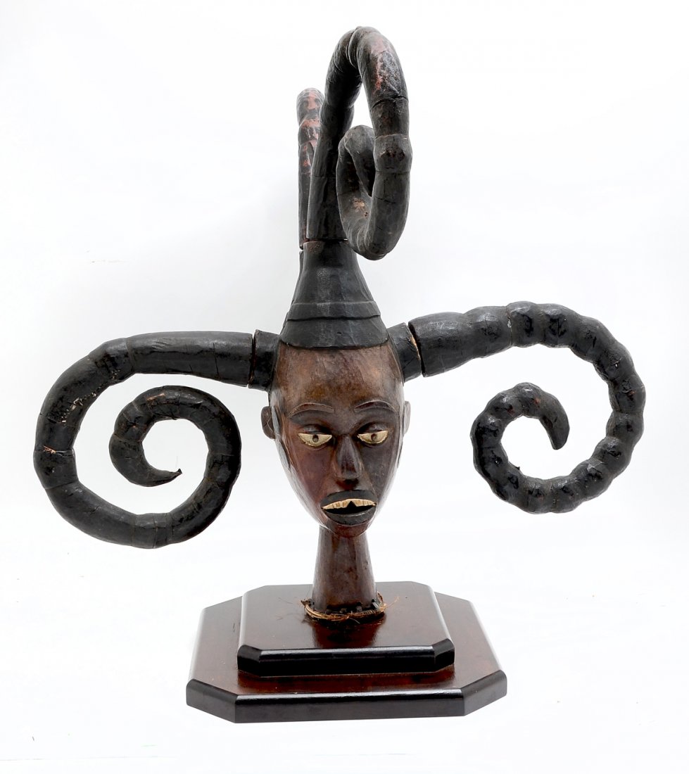 CARVED BUST IN THE LATE STYLE OF ELAGHEM PEOPLES: CARVED BUST IN THE LATE STYLE OF ELAGHEM PEOPLES OF NIGERIA: Carved African figure in the style the Elaghem peoples of Nigeria, having 4- attached curling arms at head. Attached on a tiered base. Appr