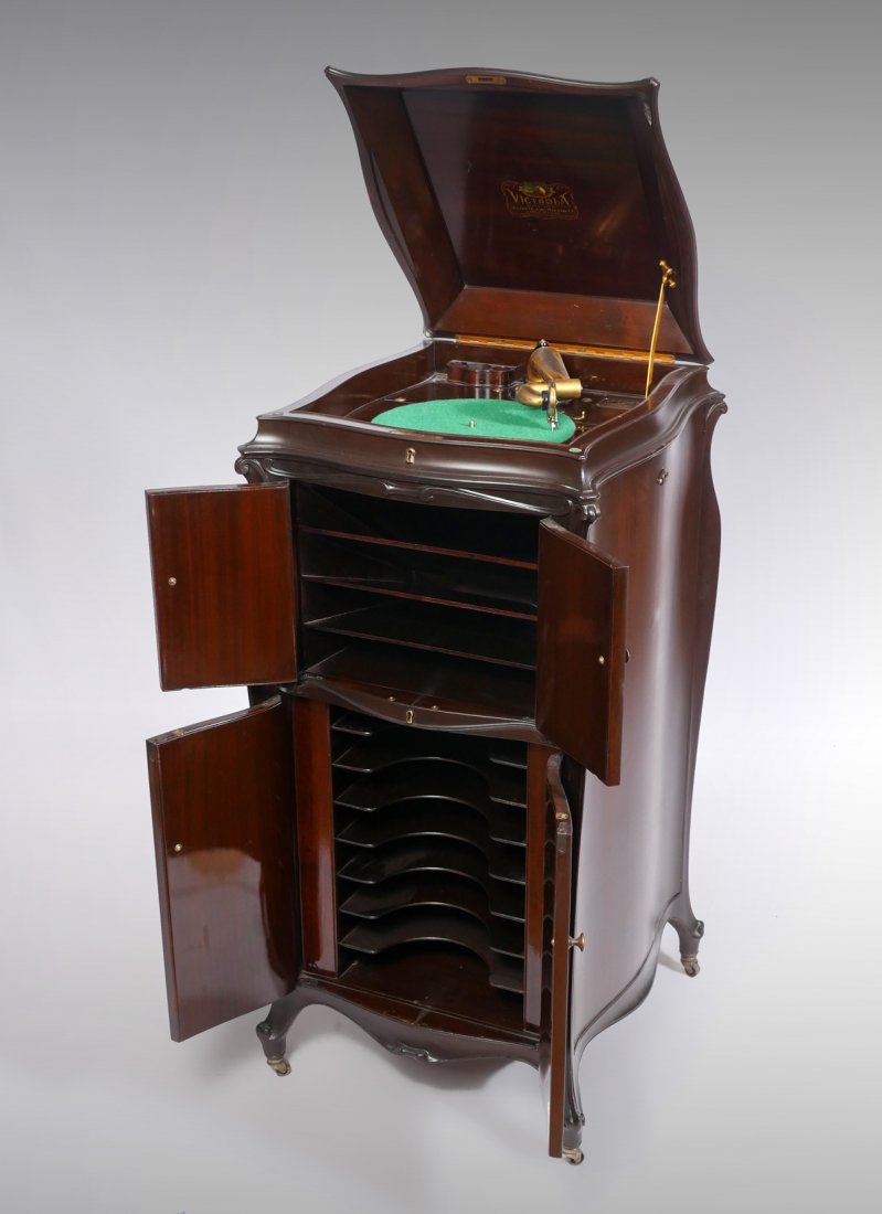 MAHOGANY 4-DOOR NO.2 VICTROLA: MAHOGANY 4-DOOR NO.2 VICTROLA: No.2 Victrola in a mahogany cabinet, having a carved foliate design to corners. Upper doors reveal a sectioned horn. Lower doors reveal a 7-shelf storage compartment. VV