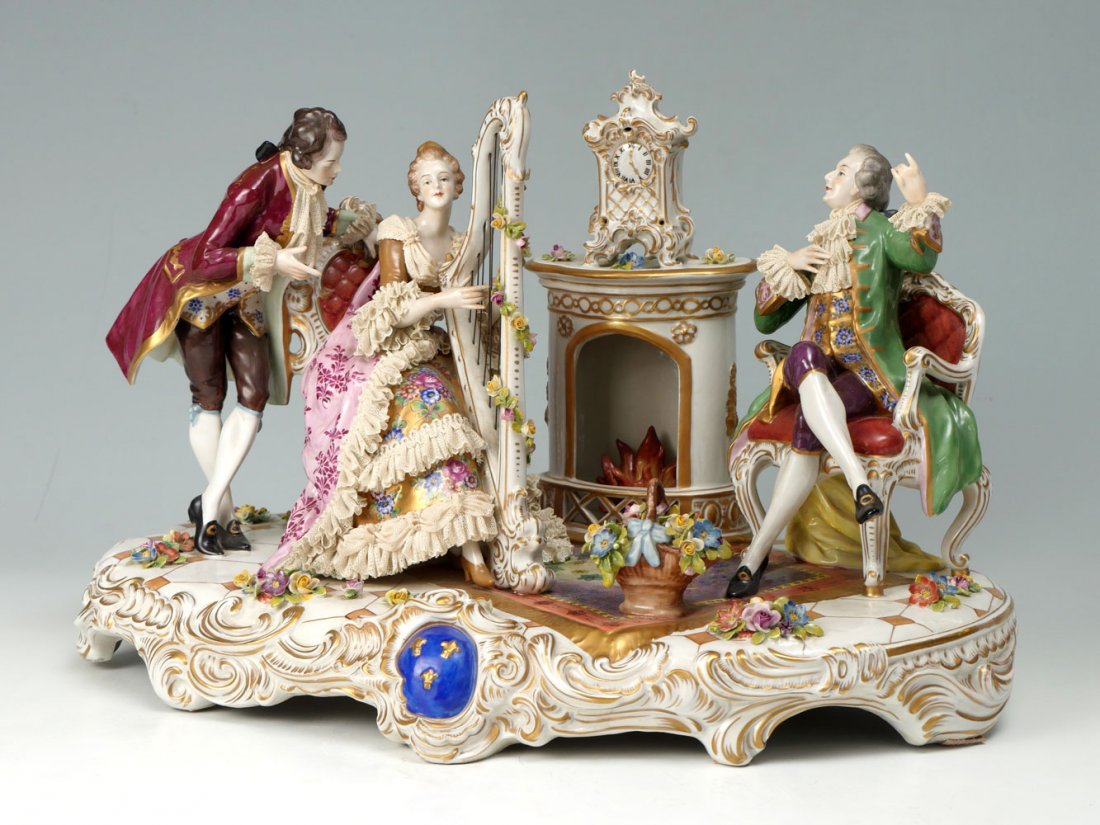 VOLKSTEDT PORCELAIN GROUPING UNDER CUSTOM CASE: VOLKSTEDT PORCELAIN GROUPING UNDER CUSTOM CASE: Large Volkstedt Dresden porcelain, having a figural fireside parlor scene. Seated female playing a harp. Attached lace & painted gold accents throughout