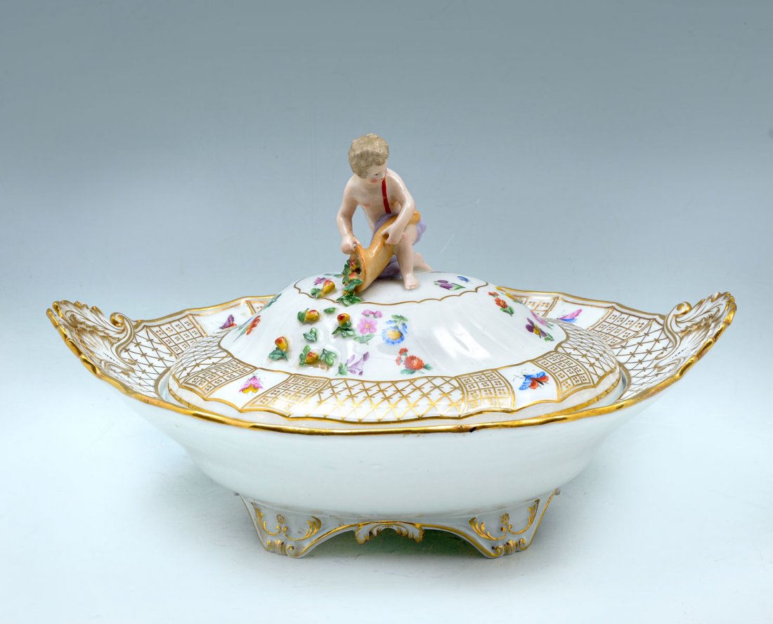 MEISSEN FIGURAL COVERED VEGETABLE DISH: MEISSEN FIGURAL COVERED VEGETABLE DISH: Meissen covered vegetable dish, crossed swords mark at underside. Painted butterflies & insects at lid, with a cherub, fruit, & cornucopia finial. Approx. 7.5''