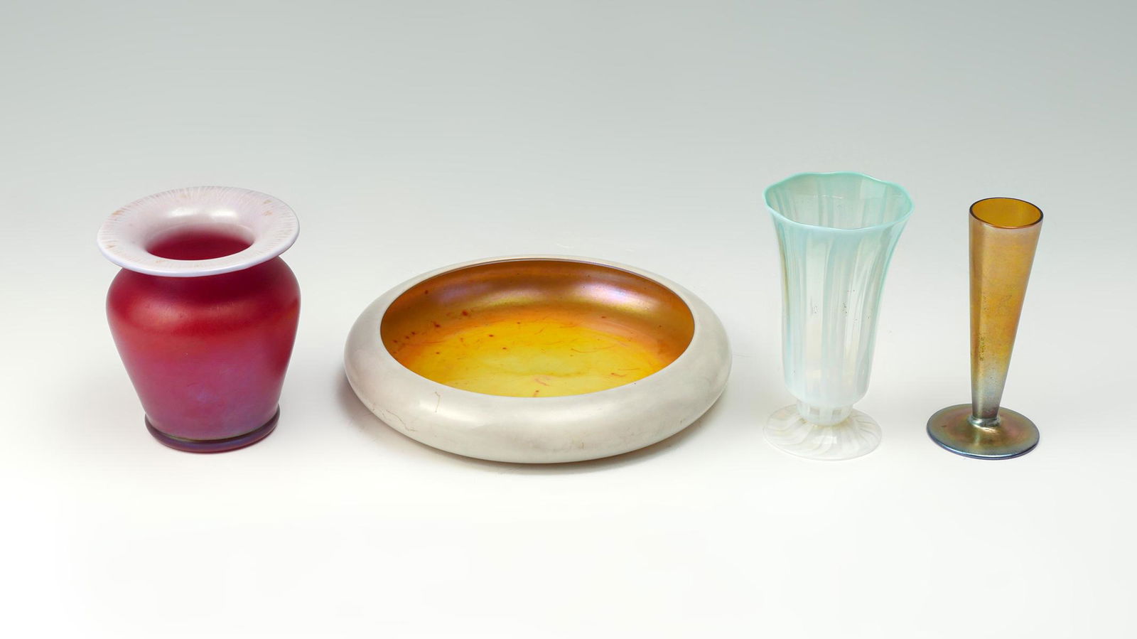 4 PC. ART GLASSES INCLUDING TIFFANY & STEUBEN: 4 PC. ART GLASSES INCLUDING TIFFANY & STEUBEN: Comprising; 1- Steuben calcite low bowl with a gold aurene interior. 1- Ruby red art glass vase with a calcite interior. 1- Ribbed blue & white striped f