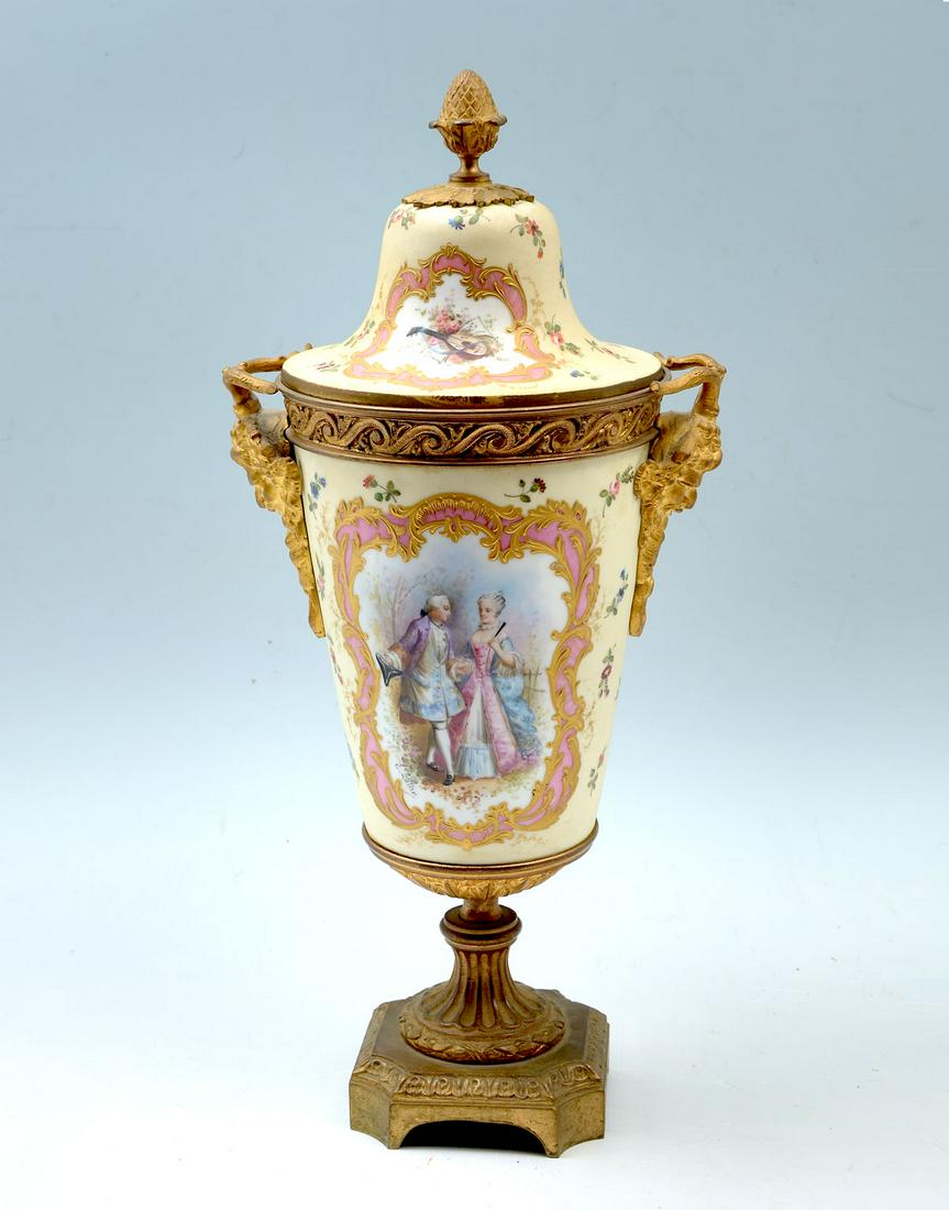 SEVRES BACCHUS ORMOLU MOUNTED COVERED URN: SEVRES BACCHUS ORMOLU MOUNTED COVERED URN: Large Sevres porcelain vase having a cream ground with a hand-painted courting scene at the observe, and a countryside pond with an urn in the distance. Gilt
