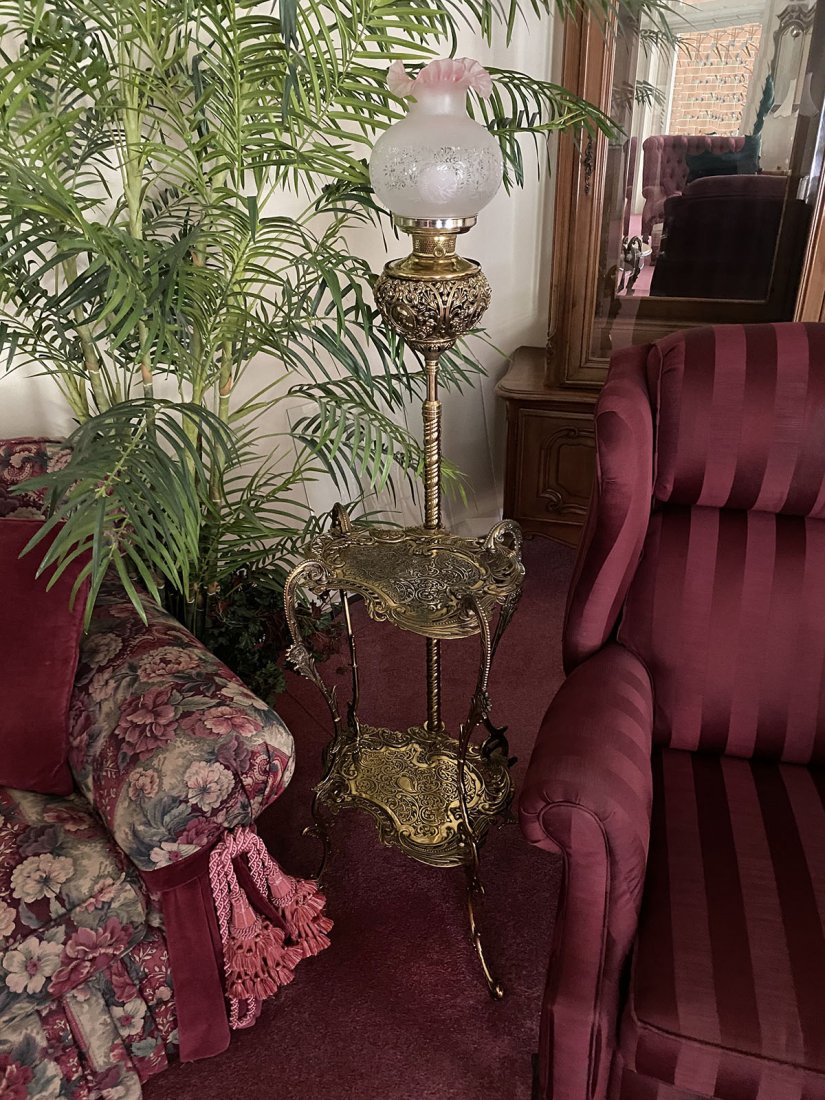 ORNATE BRASS 2 TIER PIANO LAMP TABLE: ORNATE BRASS 2 TIER PIANO LAMP TABLE: Having an overall scrolling foliate design. Spiraling ribbed light post surmounted by a frosted shade with a ruffled rim. Approx. 65" h x 21.25" l x 19.75" w.