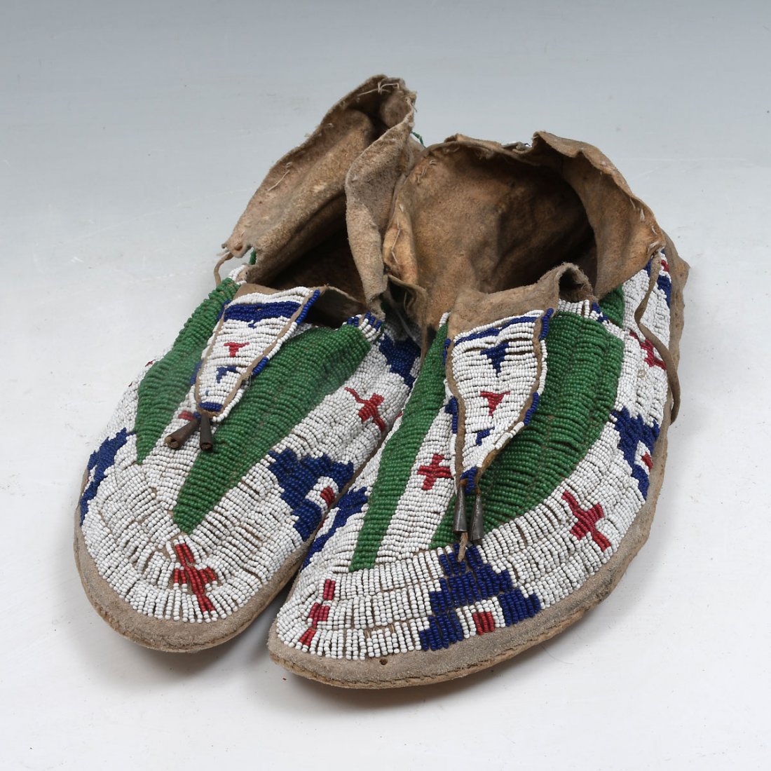 AMERICAN INDIAN SIOUX BEADED MOCCASINS: AMERICAN INDIAN SIOUX BEADED MOCCASINS: Classic design, sinew sewn and lazy stitch beaded elk hide moccasins with hard soles, a beaded tongue and beautiful geometric pattern. 11.5"