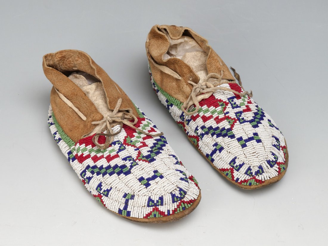 AMERICAN INDIAN SIOUX BEADED MOCCASINS: AMERICAN INDIAN SIOUX BEADED MOCCASINS: Ca. 1930s, Classic design, sinew sewn and lazy stitch beaded elk hide moccasins with hard soles and beautiful geometric pattern. 10".