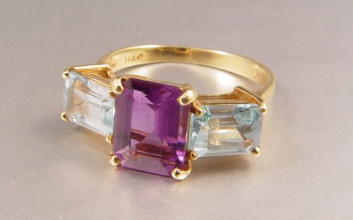 AMETHYST & BLUE TOPAZ 14K RING: 2.5 CT AMETHYST WITH BLUE TOPAZ RING: 14K yellow gold ring centers an emerald cut amethyst. Weight: 2.50 Ct. Approx. The amethyst is flanked by 2 emerald cut topaz. Weight: 2.50 Ct. Approx. The gemsto