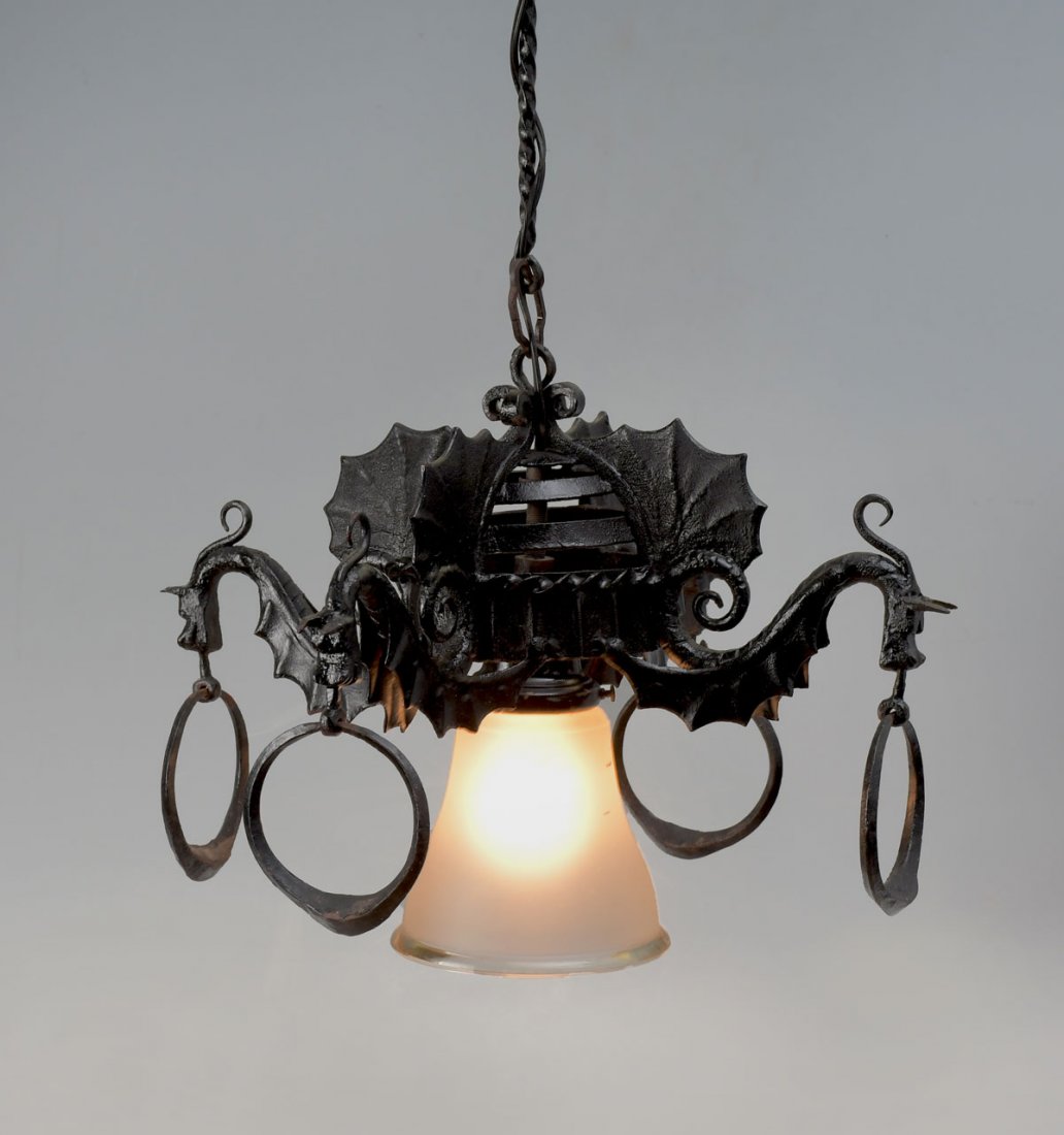 METAL DRAGON MOTIF HANGING LIGHT FIXTURE: METAL DRAGON MOTIF HANGING LIGHT FIXTURE: Single light forged iron chandelier, having 4- dragon form scrolling arms. Each with large ring in mouth. Approx. 26" h x 16.25" w.