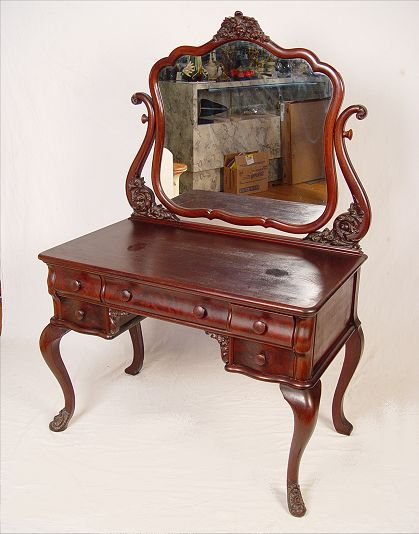 HORNER QUALITY ELEGANTLY CARVED MAHOGANY VANITY: TURN OF THE CENTURY ELEGANTLY CARVED MAHOGANY VANITY: With swing mirror. A fine Horner quality piece with simple floral carved accents to the mirror harp and base of feet. 60 1/2" x 40" x 23".