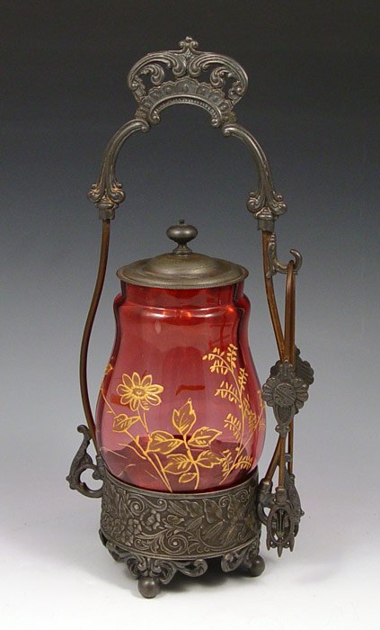BABOUR SILVERPLATE & CRANBERRY GLASS PICKLE CASTOR: BABOUR SILVERPLATE & CRANBERRY GLASS PICKLE CASTOR AND TONGS: The cranberry glass with enamel decoration, 4 3/5". Babour frame and holder has lost its silver plating, as has the tongs. 11 3/4" tall ov