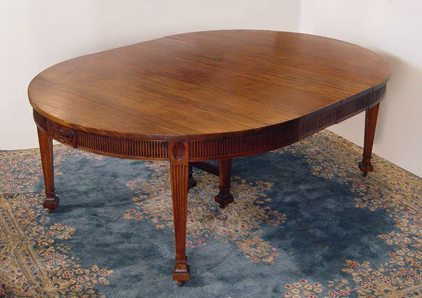 WATERTOWN SLIDE 5 FT ROUND DINING TABLE: WATERTOWN SLIDE ROUND FEDERAL STYLE 5 FT ROUND DINING TABLE: Expandable mahogany round table with 2 leaves. Ribbed apron, Carved Grecian urns, reeded tapered legs ending in square pad feet and casters