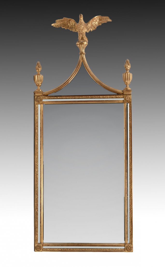 CARVED GILT BELGIAN EAGLE MIRROR: CARVED GILT BELGIAN EAGLE MIRROR: Carved floral frame with floral medallions. Surmounting Eagle, flanked by torch form finials. Made in Belgium stamp at verso. Approx. 48.25" h x 20.25" l x 4.25" w.