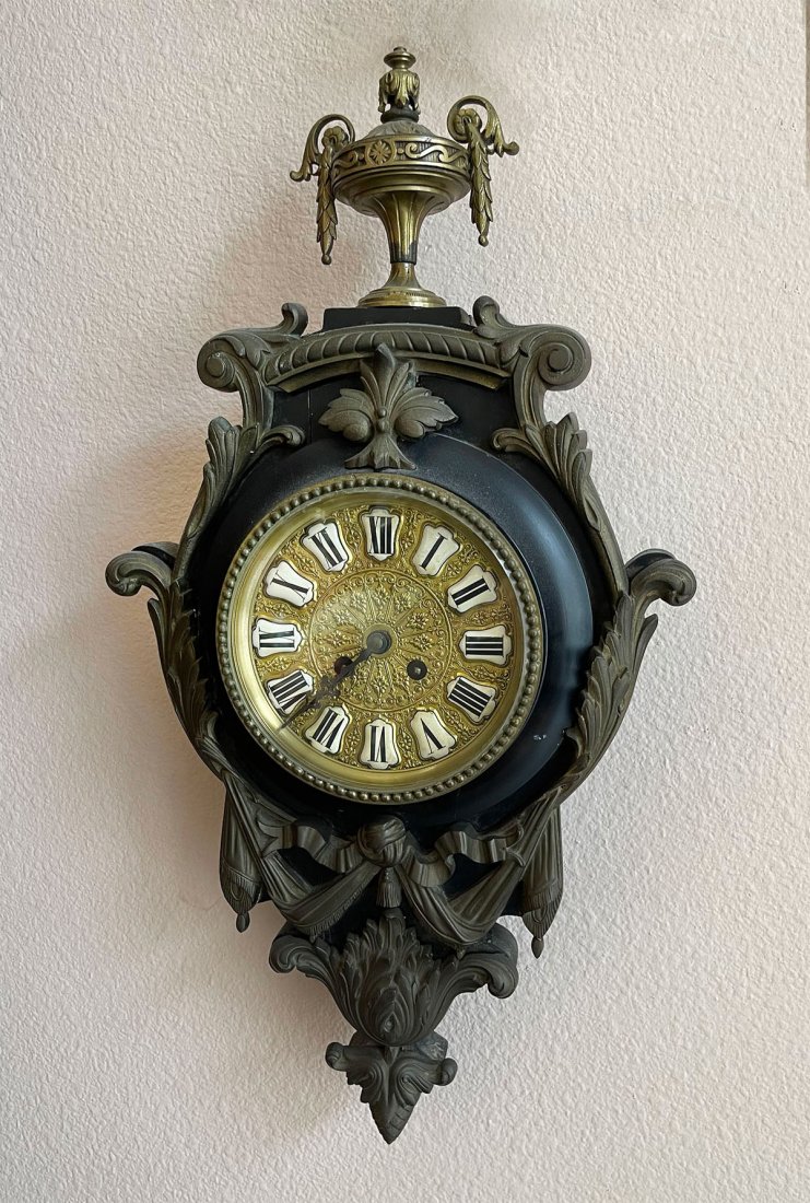 WALNUT WALL CLOCK WITH URN FINIAL: WALNUT WALL CLOCK WITH URN FINIAL: Black lacquered wood clock with brass foliate design. Surmounted by an Urn. Approx. 22.75" h x 11.75" l x 4.5" w.