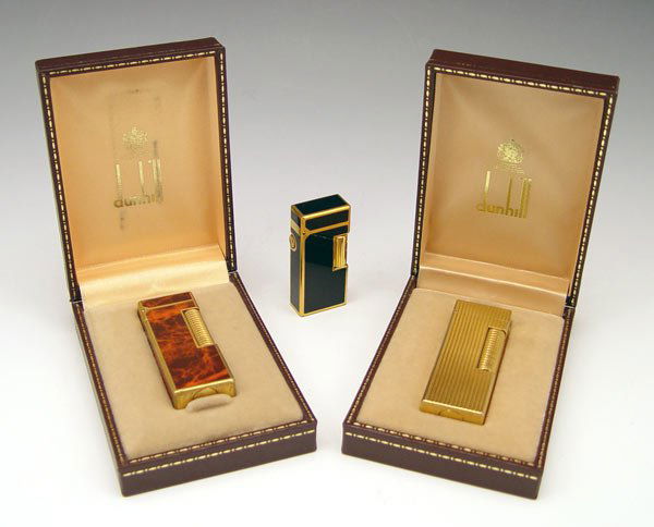3 PIECE DUNHILL ROLLAGAS LIGHTERS: 3 PIECE DUNHILL ROLLAGAS LIGHTERS: To include 1) Burl wood lacquer case with original box. 2) Gold toned, reeded case with original box. 3) Black lacquer case, no box.